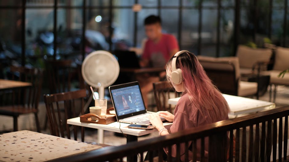 musician working on laptop with headphones in cafe