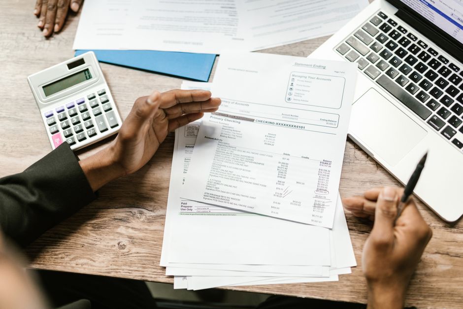 small business owner reviewing cash flow forecast on laptop with bank statements