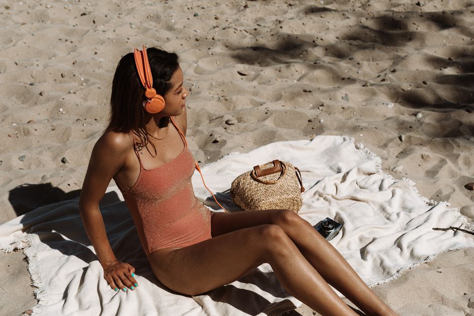 person relaxing on beach with notebook and headphones towel sunny afternoon