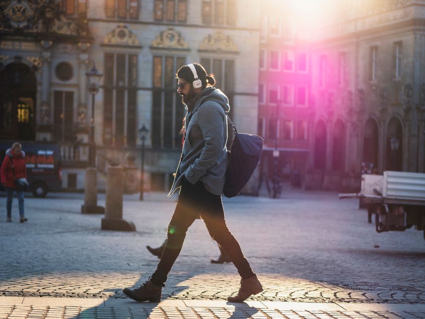 pexels-907526 person listening to music on headphones walking city street golden hour lifestyle