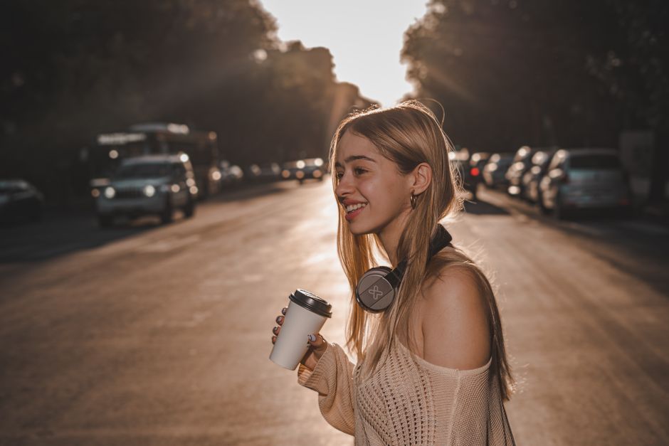 person listening to headphones while walking city street golden hour