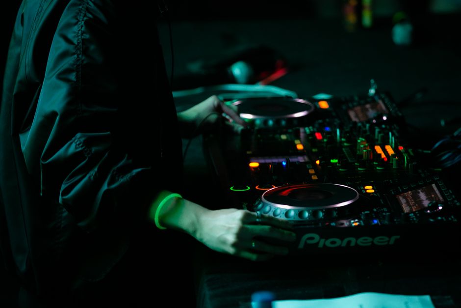 person curating music playlists with laptop and headphones nightlife aesthetic