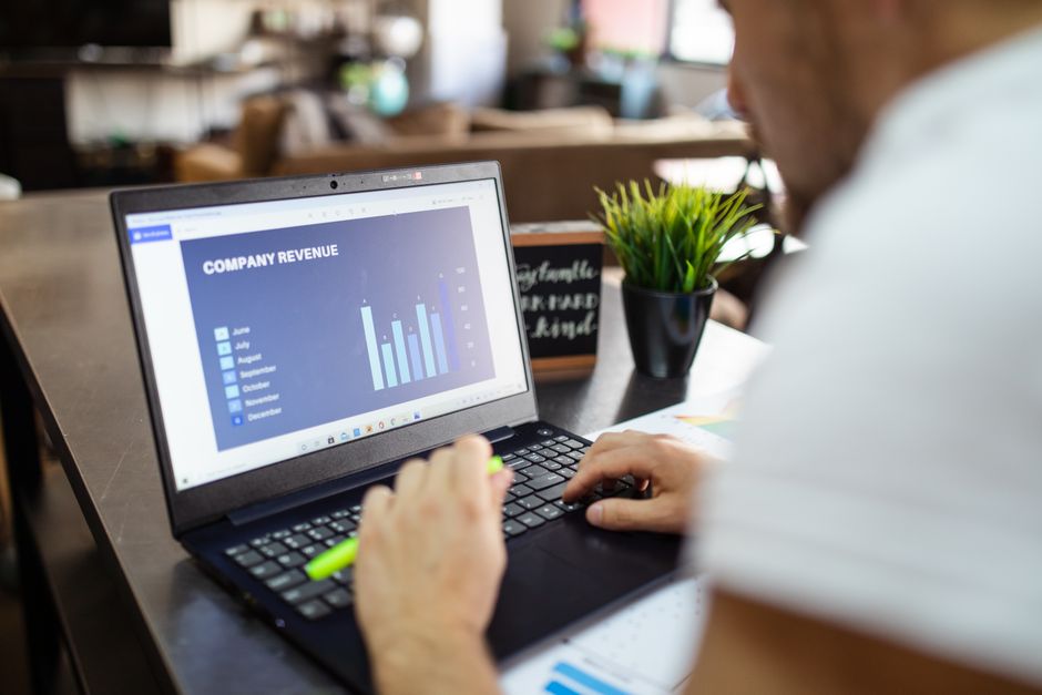small business owner reviewing subscription revenue on laptop cash flow chart
