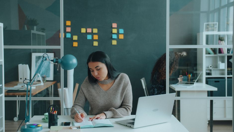 pexels-39853370 person working on laptop with AI workflow diagrams sticky notes modern office